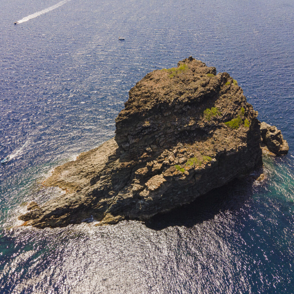Vista aerea del Faraglione di Pantelleria, una formazione rocciosa imponente circondata dal mare blu intenso