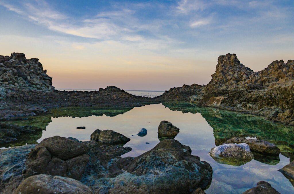 Piscine naturali di Pantelleria al tramonto, con rocce vulcaniche e acqua limpida